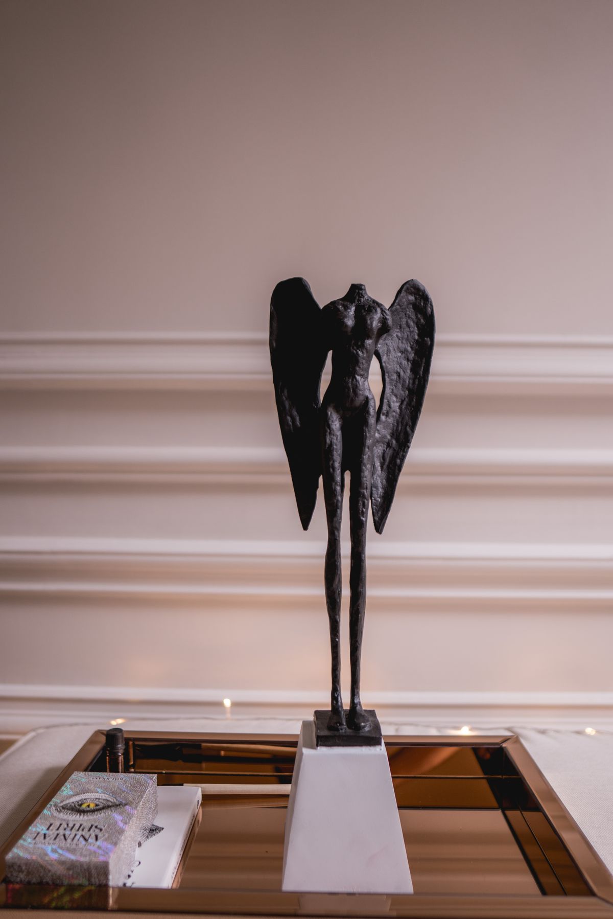 A dark bronze winged figure on a white plinth