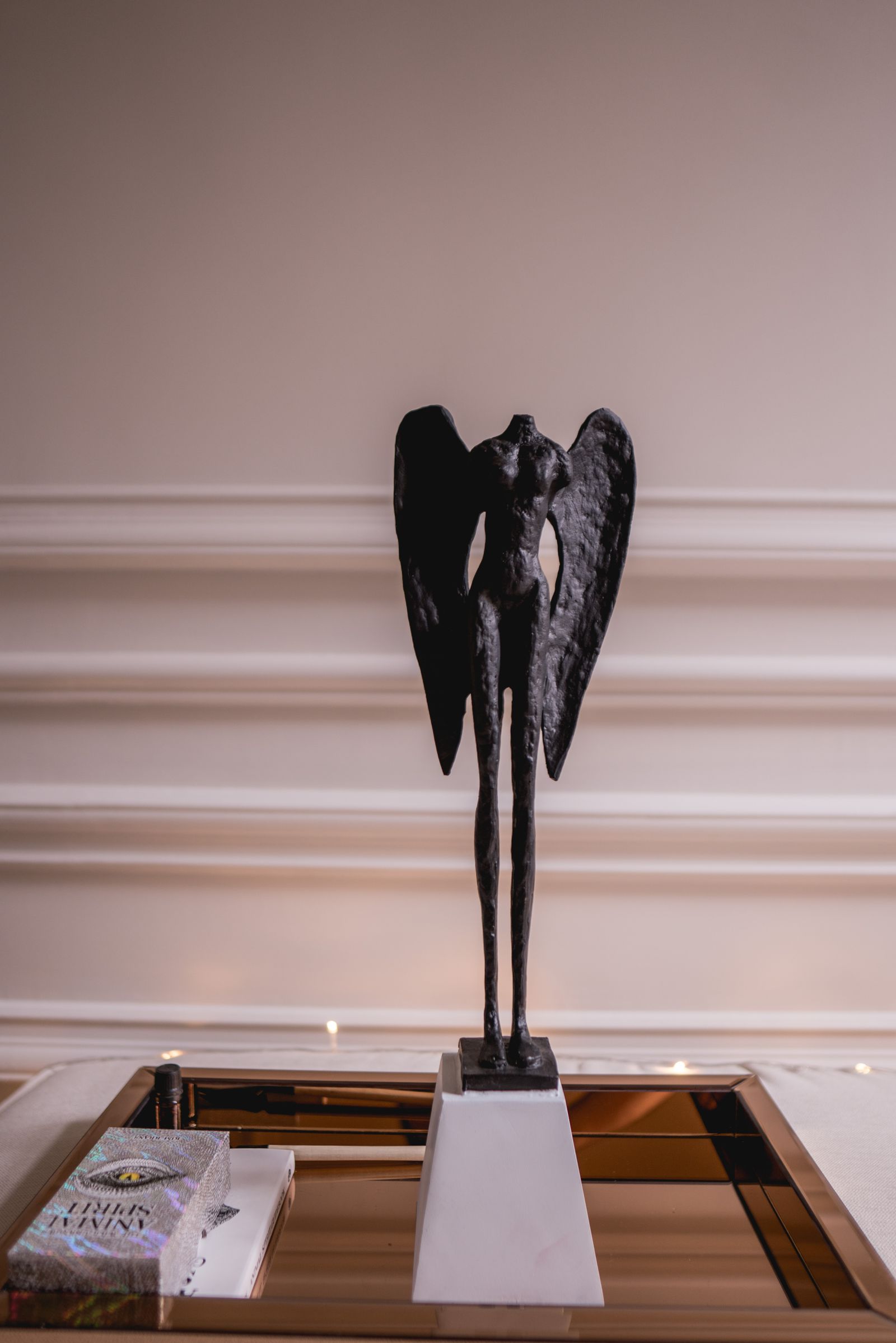 Slender dark bronze figure with wings displayed on a pale plinth