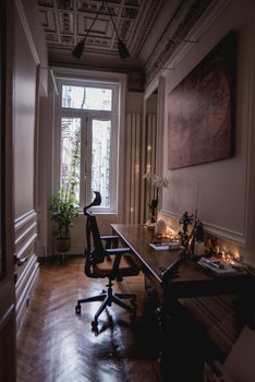 Cozy home office featuring elegant wooden furniture and natural lighting through a large window.