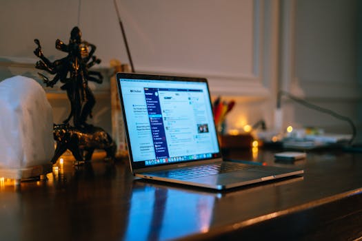 A cozy home office setup with a laptop on a wooden desk surrounded by warm lighting and decor.