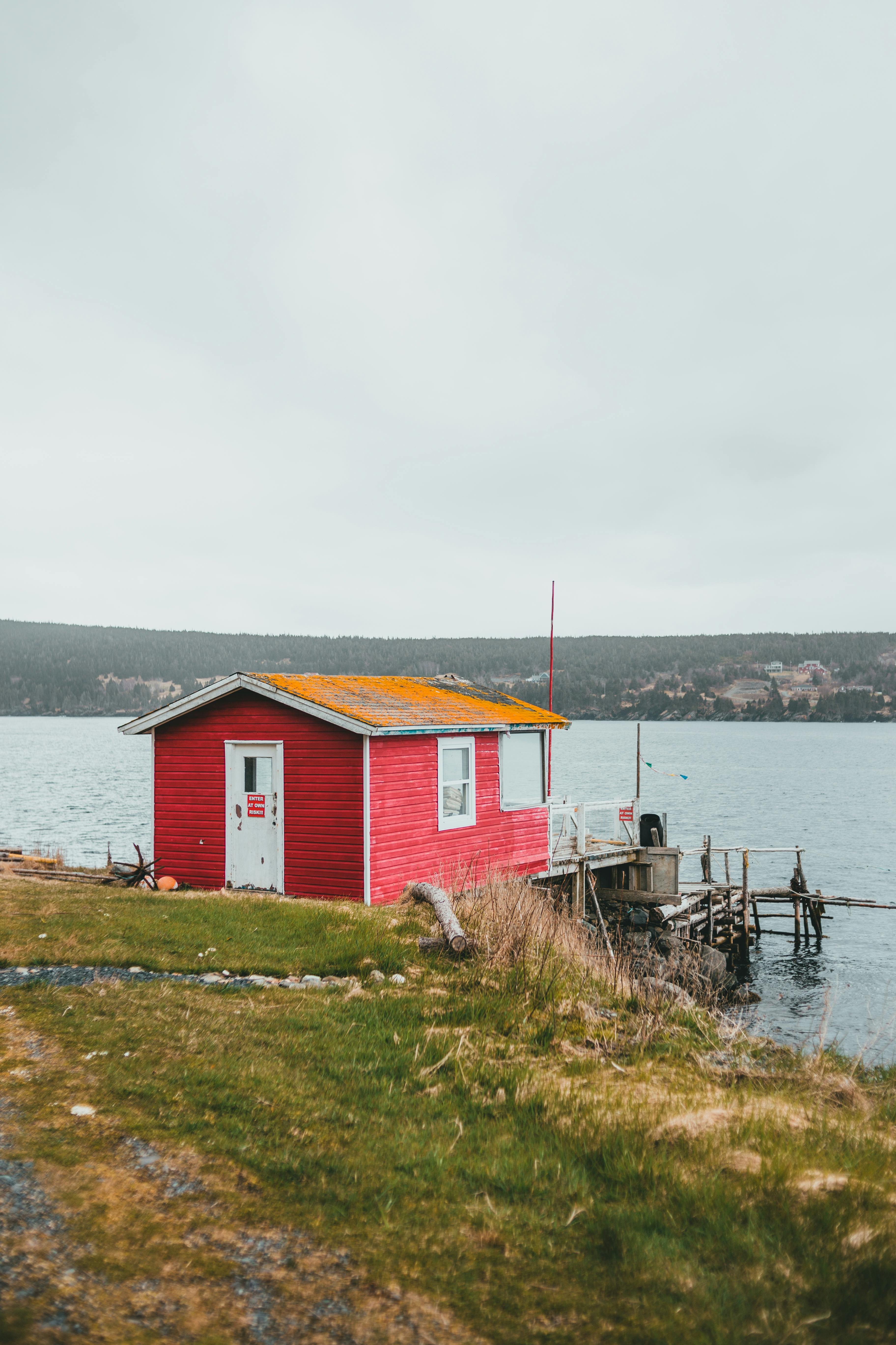 A vibrant red house stands by a peaceful lake, offering a serene natural retreat.