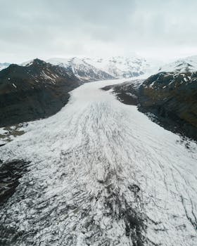 Stunning aerial view of a snow-covered glacier in a mountainous landscape during winter.