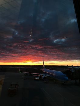 Stunning sunset view with airplane parked at Norwegian airport terminal.