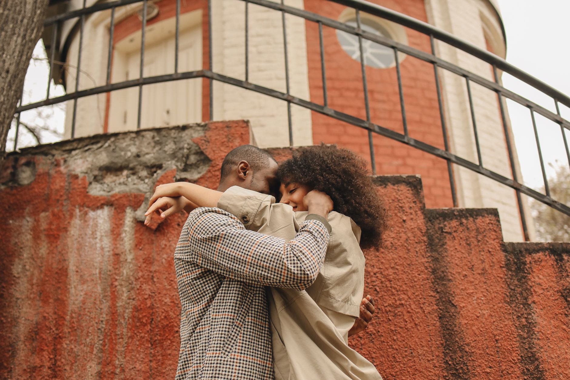 A loving couple embraces joyfully on a rustic staircase outdoors.