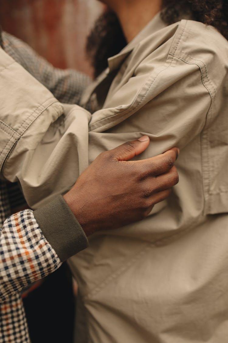 Hand Holding Person In Brown Jacket