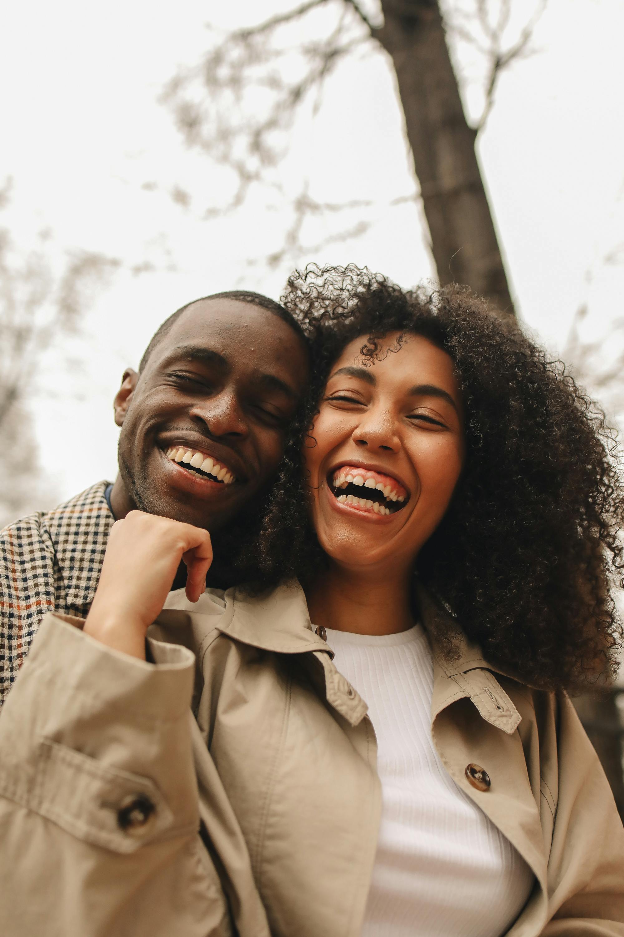 Joyful moment of a young African American couple smiling and bonding outdoors in a natural setting.