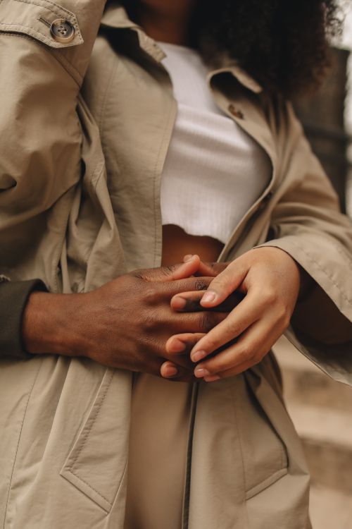 Free A close-up photo of an interracial couple warmly holding hands, showcasing tenderness and connection. Stock Photo
