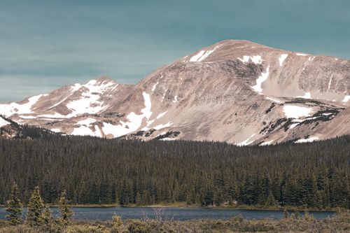 Free Beautiful mountain landscape featuring snow-capped peaks and lush forest. Perfect for nature and travel enthusiasts. Stock Photo