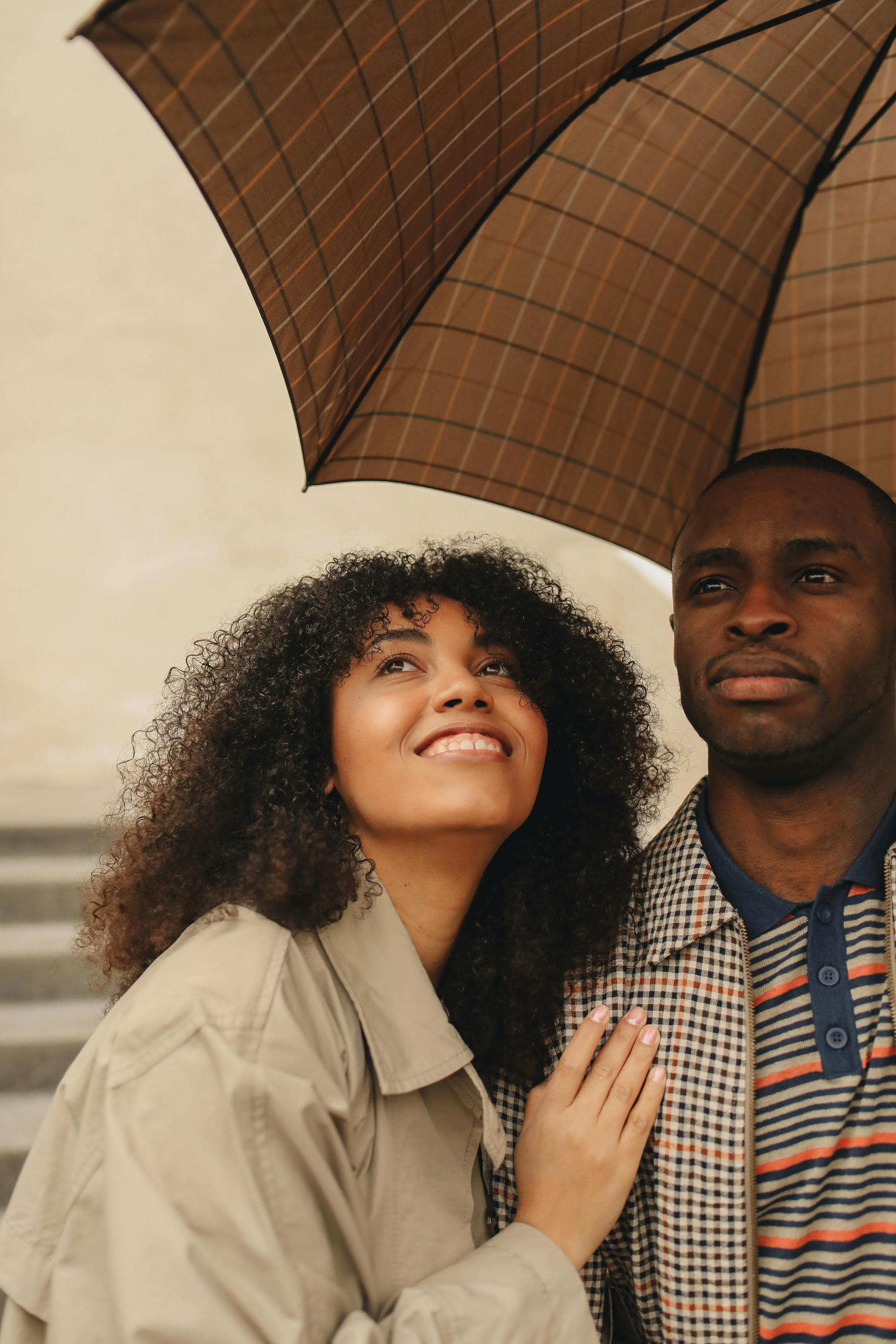 A joyful couple sharing an umbrella outdoors on a rainy day, expressing love and happiness.