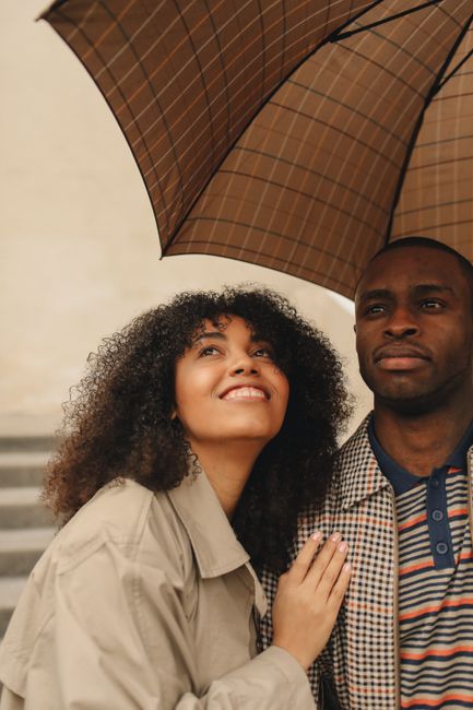 A joyful couple sharing an umbrella outdoors on a rainy day, expressing love and happiness.