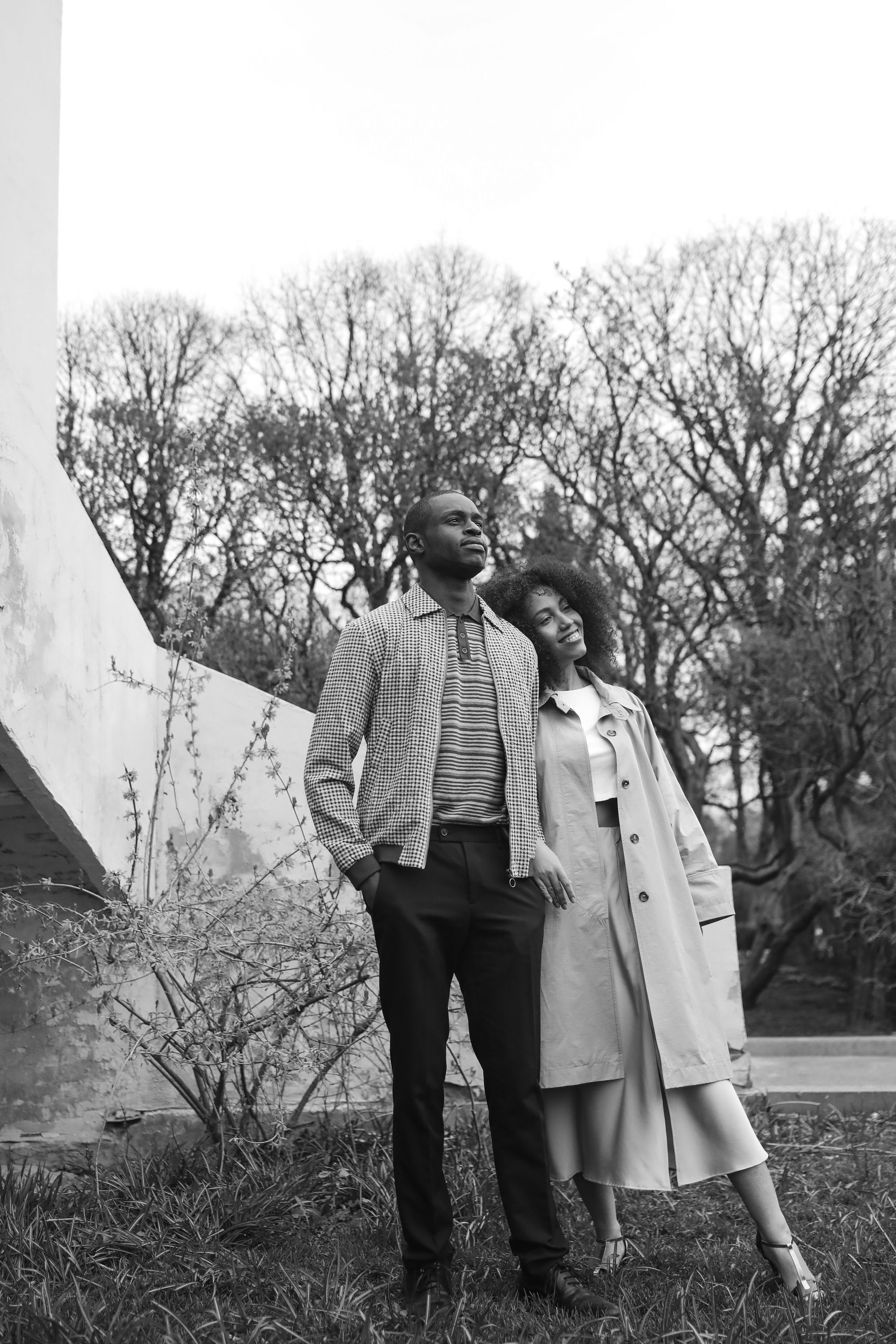 A stylish couple poses outdoors in a grayscale portrait capturing elegance and togetherness.