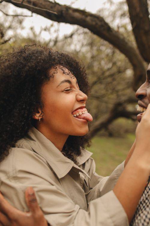 Free Young adults with curly hair enjoying a playful interaction outside in nature. Stock Photo