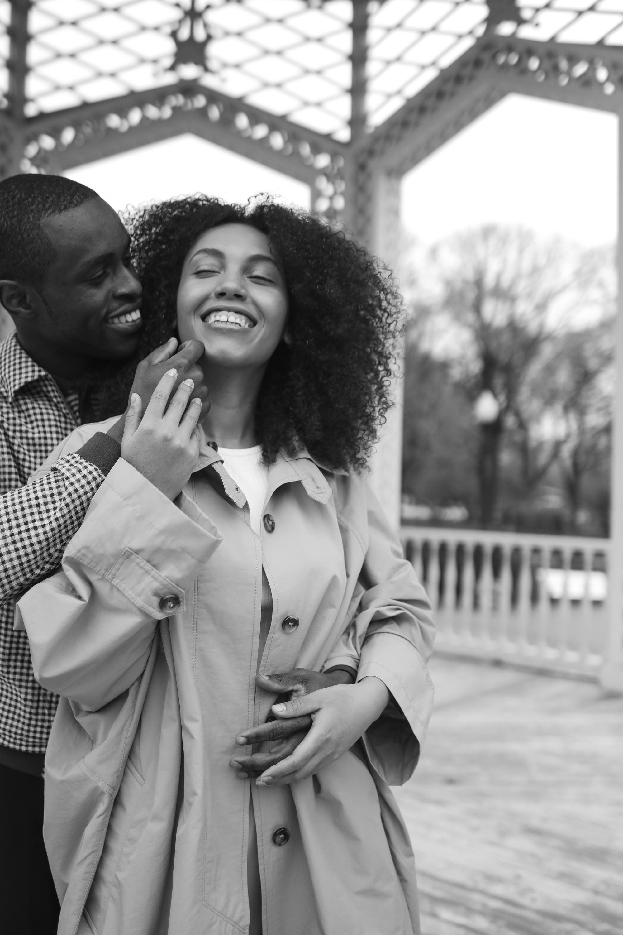 Happy couple embracing under a gazebo, showcasing love and affection.