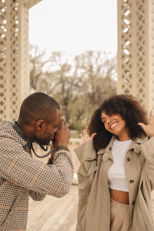 Free A happy couple enjoys a playful photoshoot in a park, capturing genuine smiles and joyful expressions. Stock Photo