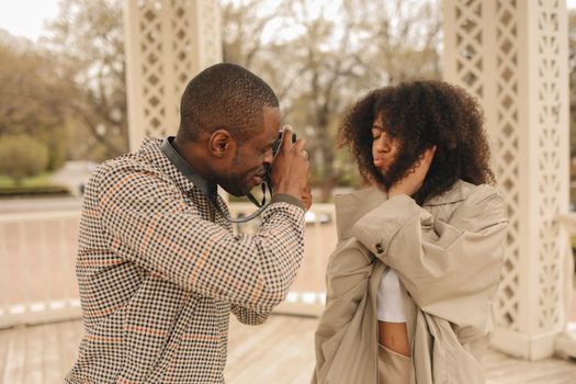 Man in Plaid Jacket Taking Picture of  Woman in Brown Coat