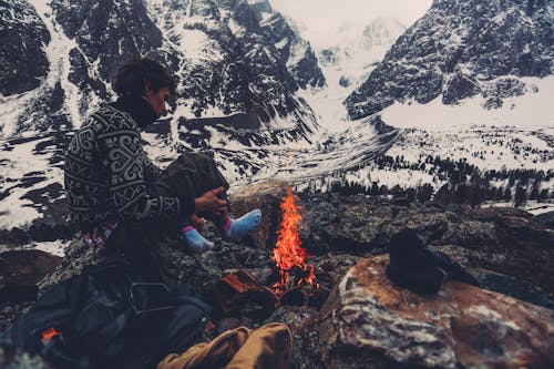 Man Sitting by a Fire in the Mountains