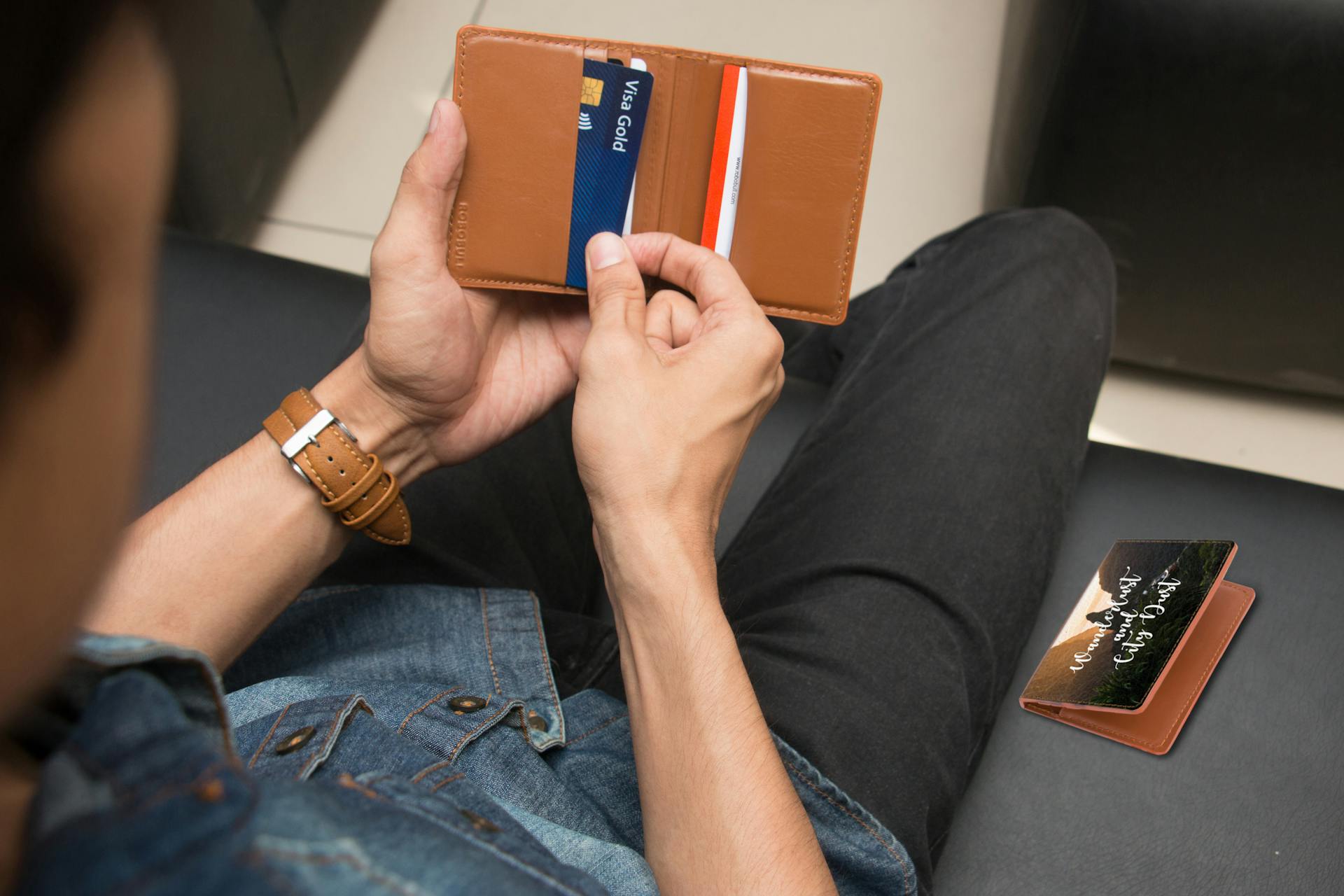 Over-the-shoulder view of a person holding a leather wallet displaying credit cards.