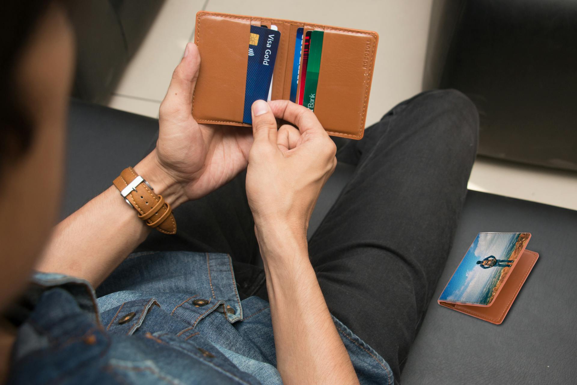 A close-up of a man holding a wallet containing credit cards and an ID inside a room.