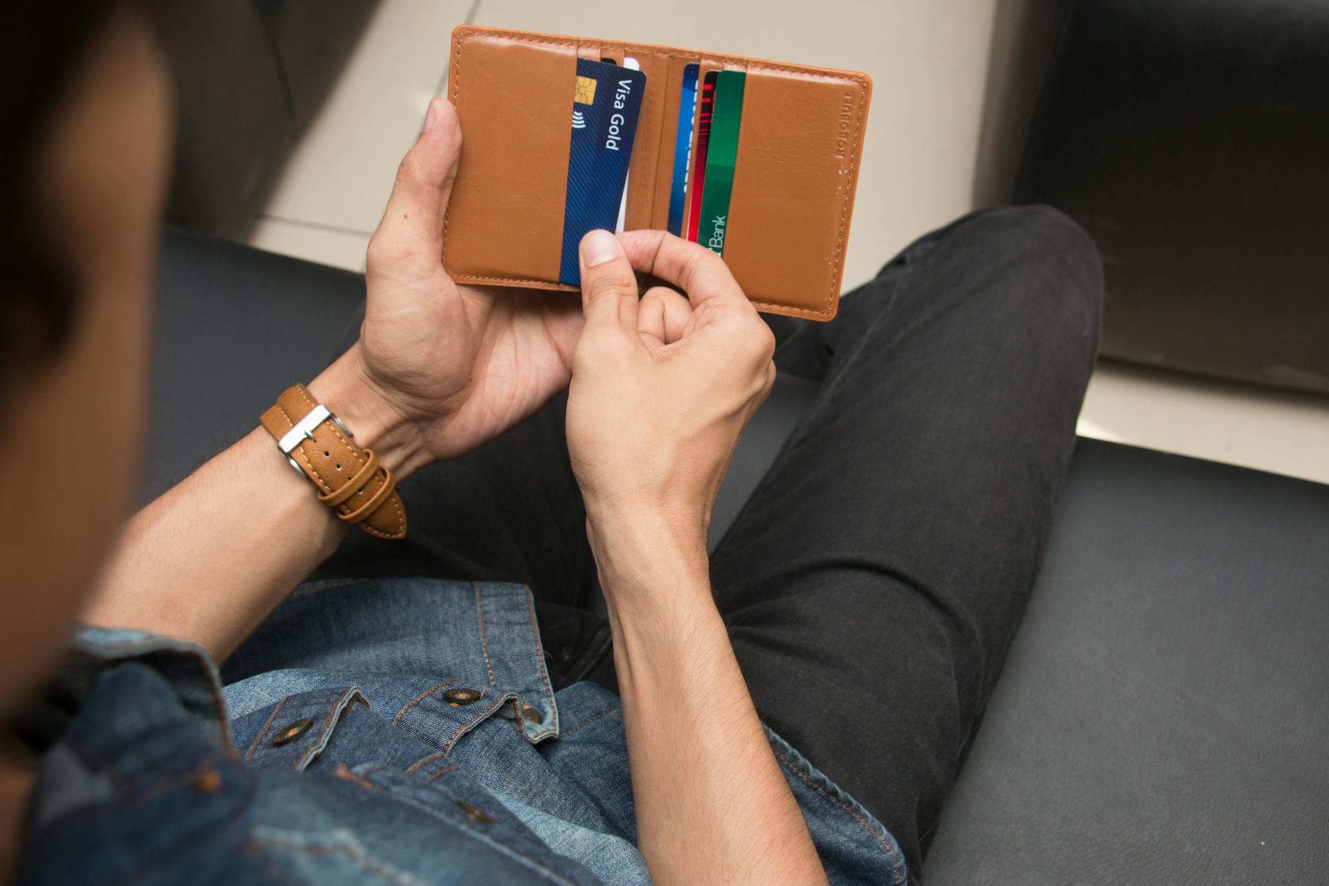 Close-up of a man holding a wallet with various credit cards, showcasing everyday finance essentials.