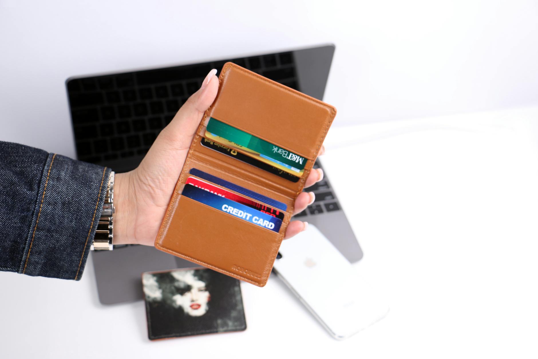 Close-up of a hand holding a leather wallet with credit cards