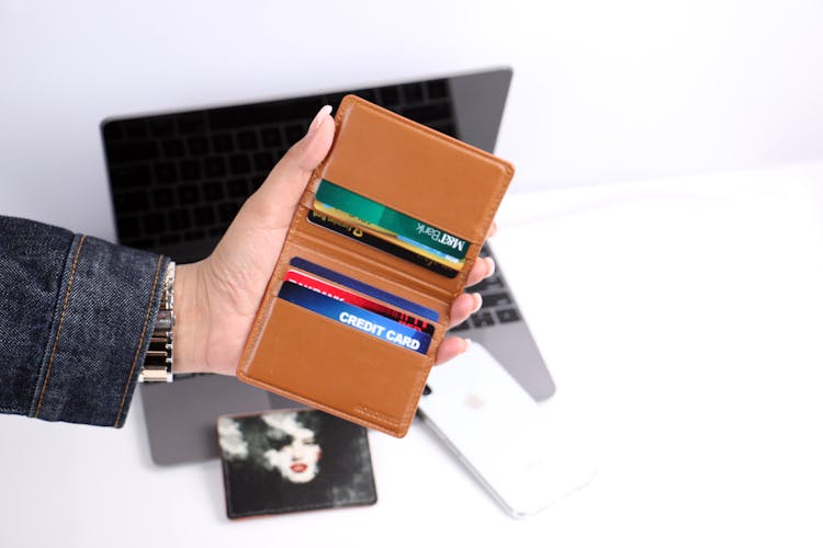 A Person Holding A Wallet With Cards