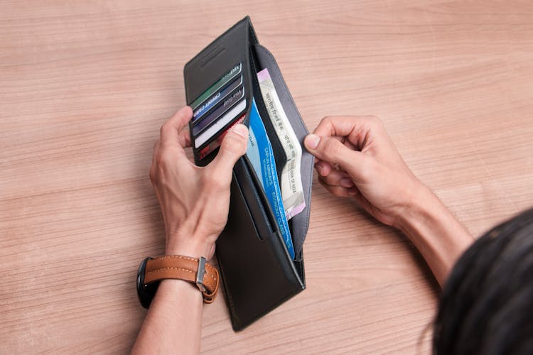 A Person Opening A Black Leather Wallet