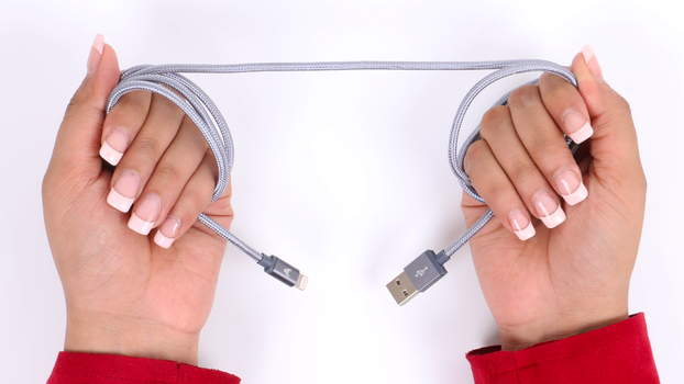Close-up of hands holding a USB cable on a white surface, highlighting connection and technology.