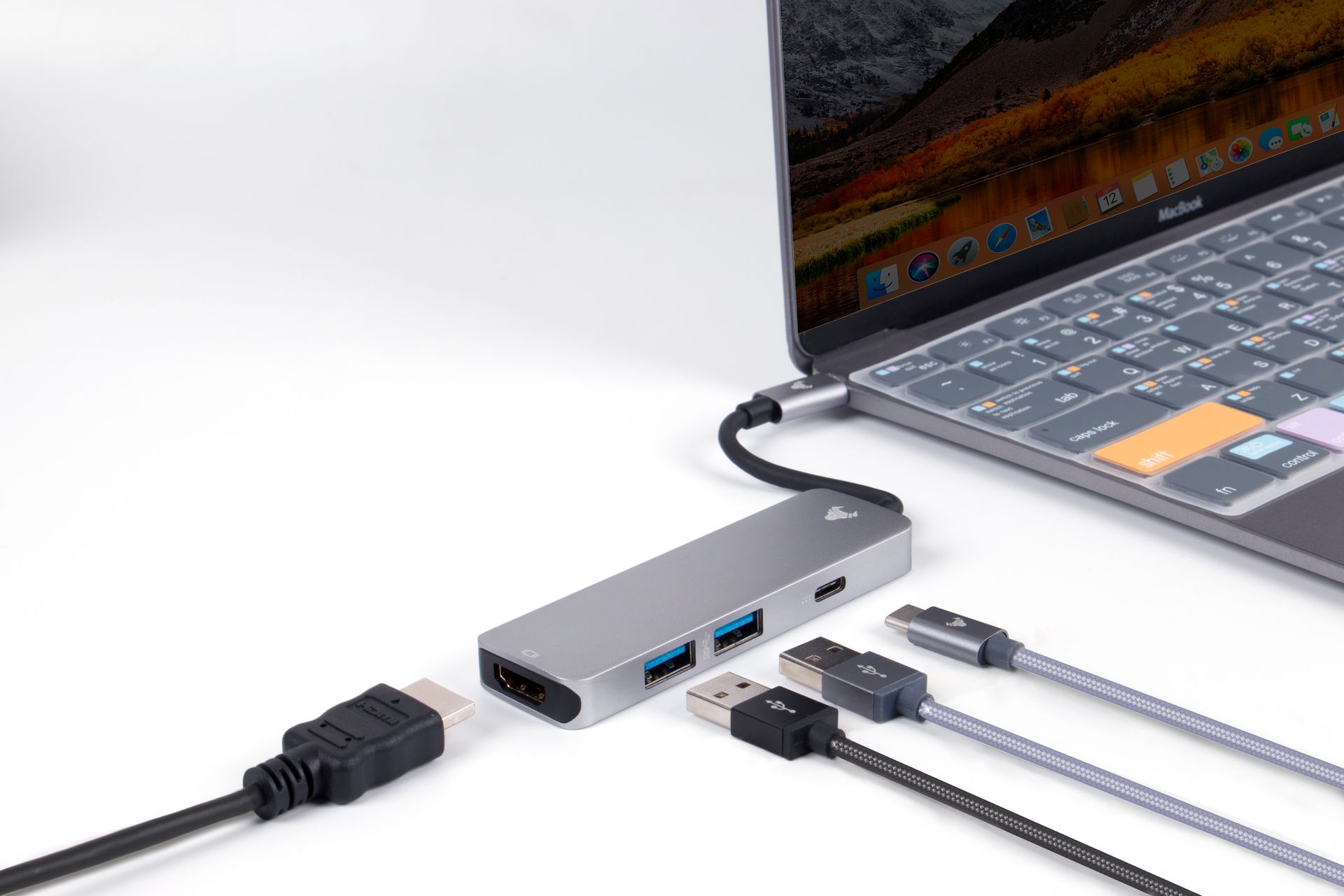 Close-up view of a USB hub connected to a laptop, showcasing various ports and cables on a white surface.