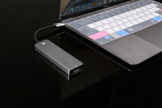 A sleek USB hub connected to a modern laptop on a reflective surface.