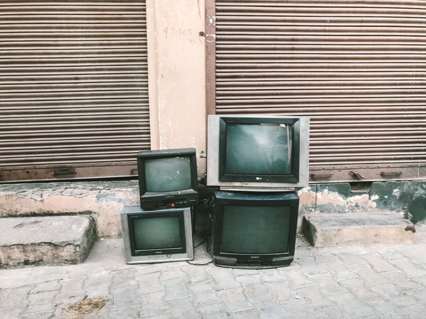 Four vintage CRT televisions discarded outside on an urban street.
