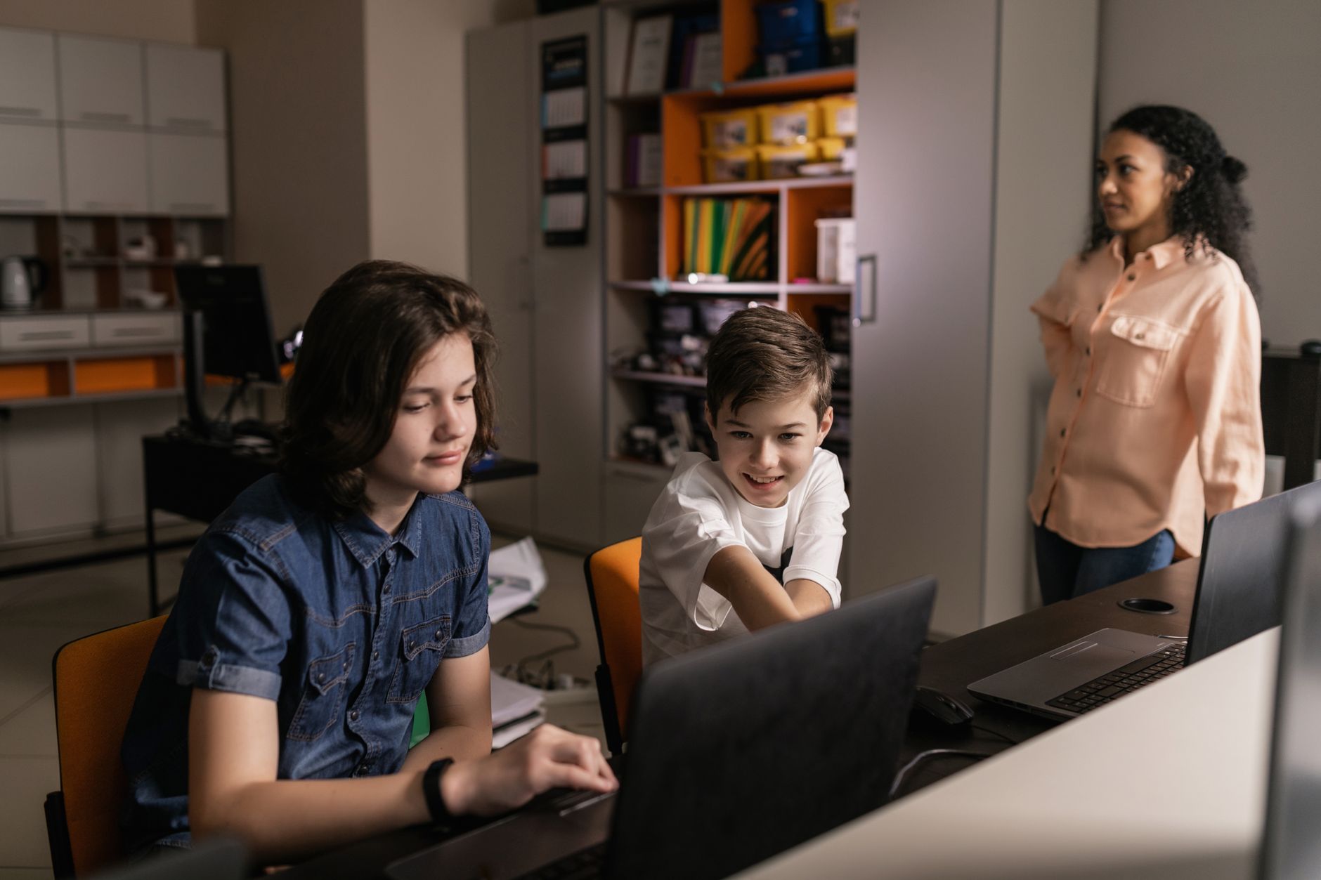 Teacher supervising students using laptops during a classroom exercise
