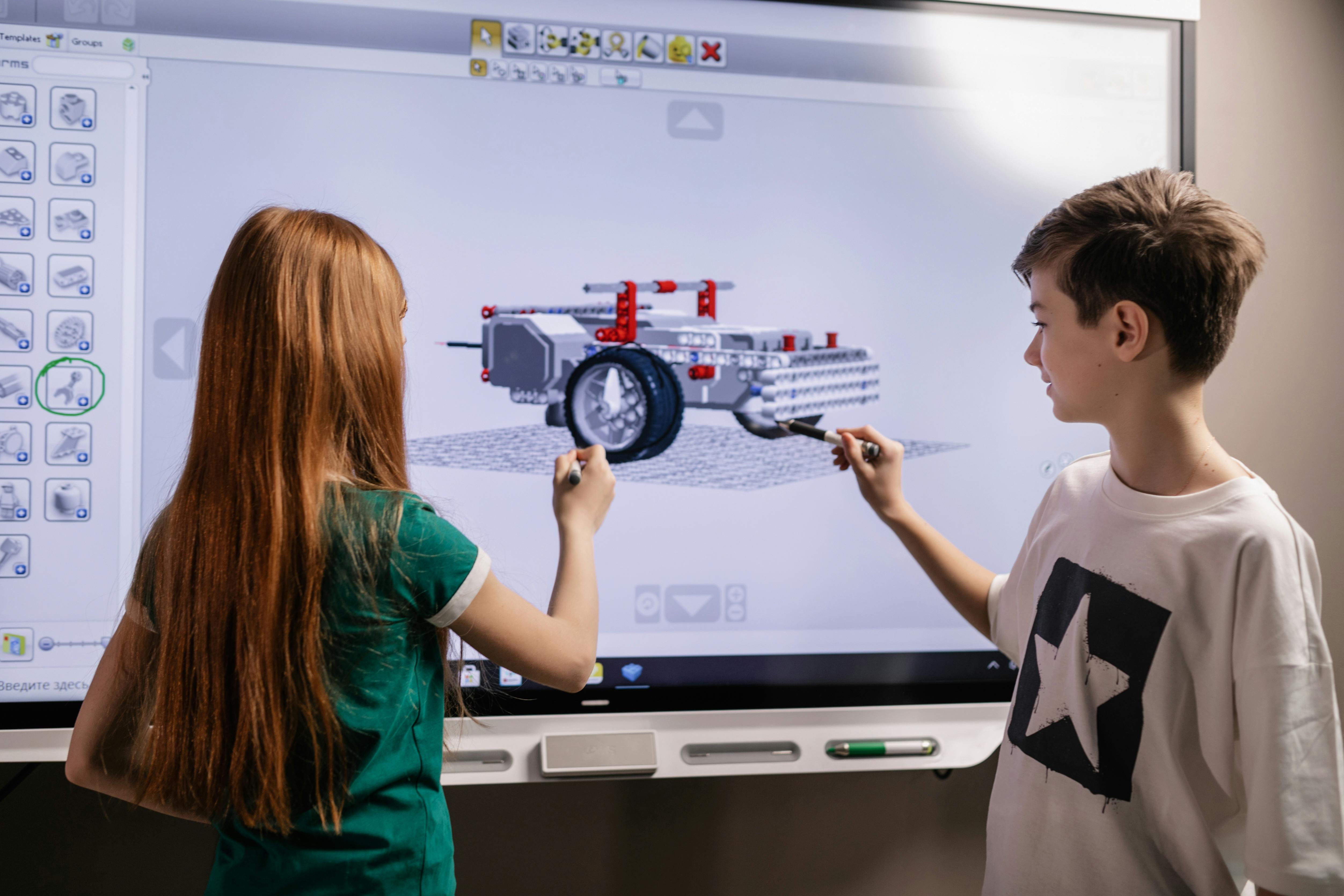 boy and girl standing in front of computer screen