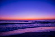 宁静的海滩日落中，充满活力的色彩映照在水面和波浪上