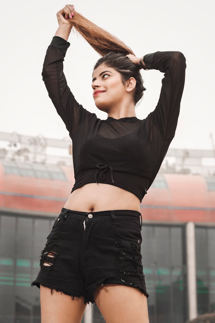 Woman In Black Crop Top And Black Denim Shorts Holding Her Hair