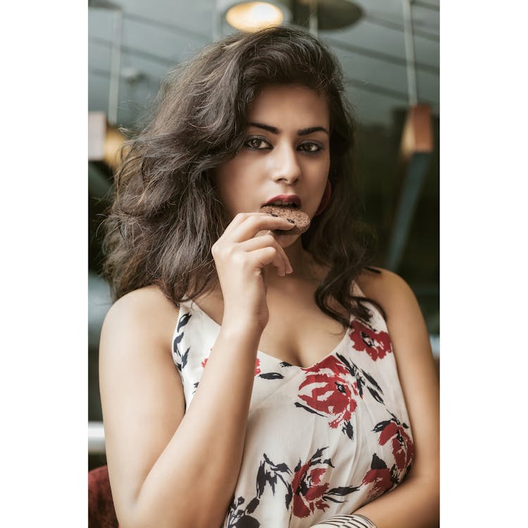 Close-Up Shot Of A Pretty Woman In Floral Top Eating A Cookie