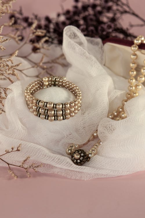 Free Sophisticated display of pearl jewelry on soft white fabric, perfect for luxury fashion and design inspirations. Stock Photo