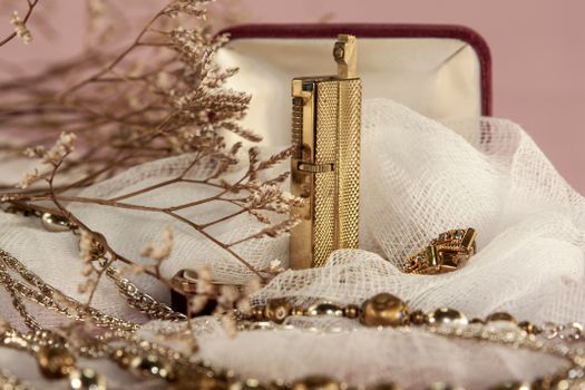 Close-up of luxurious gold jewelry and dry flowers with a soft, artistic ambiance.