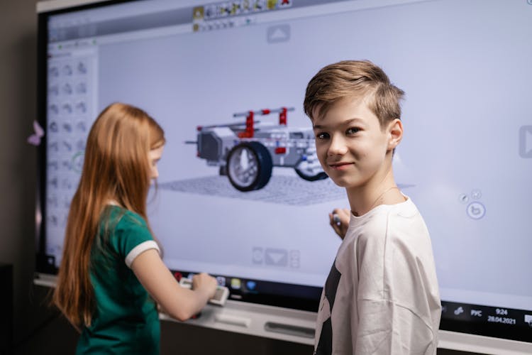 A Boy Standing Beside A Big Screen