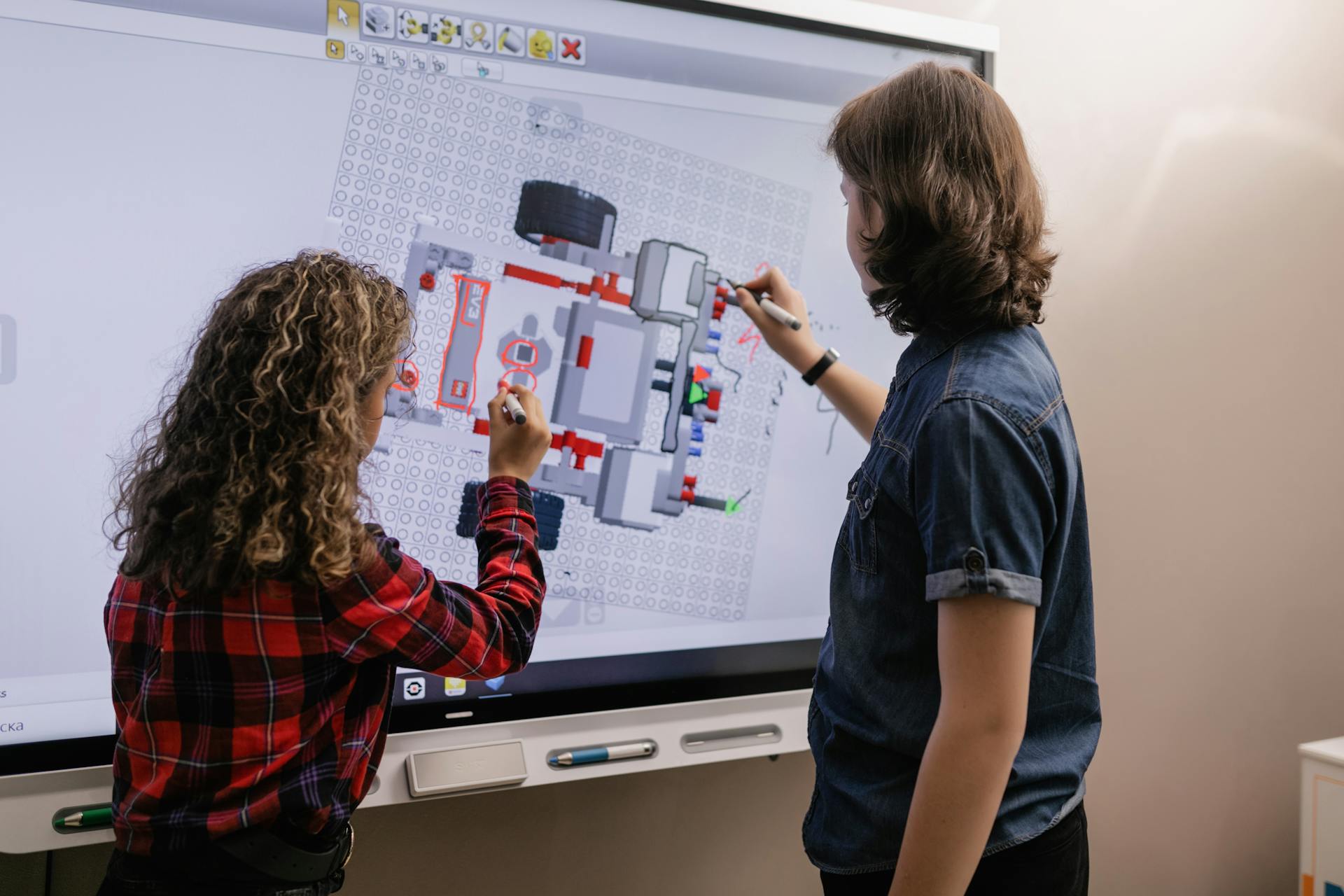 Two children engaging with a smart board in a modern classroom setting.