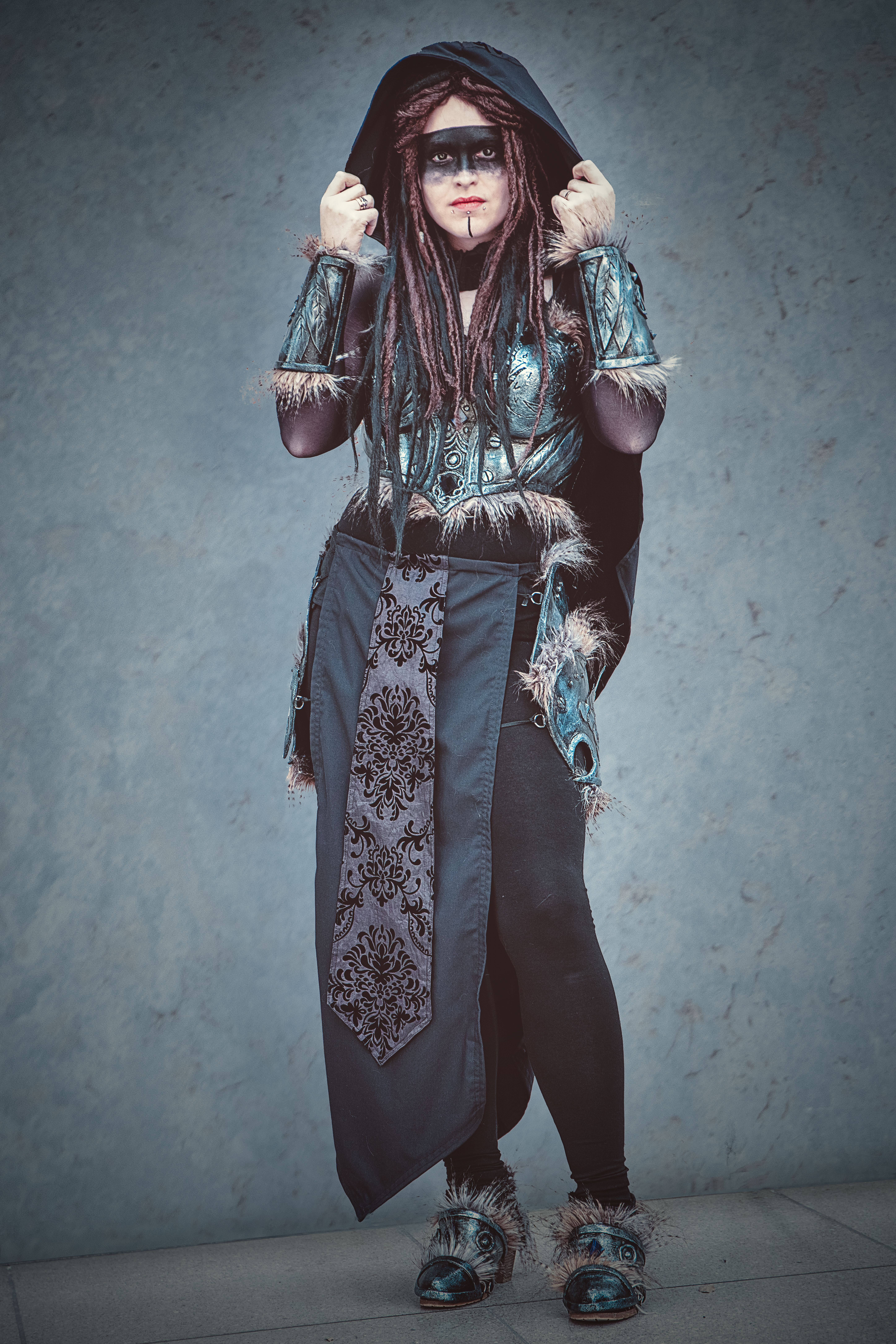 A woman in an elaborate fantasy costume poses in a studio setting.