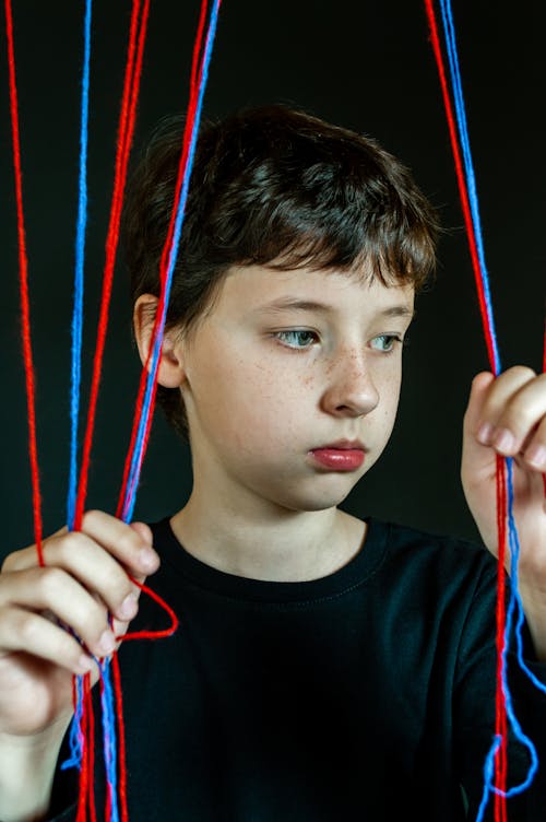 Boy holding colourful ropes against black background