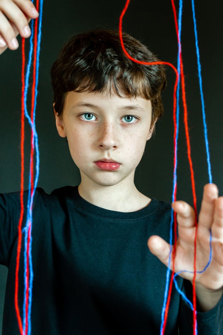 Boy In Black Crew Neck T-shirt In Front Of Red And Blue Yarns