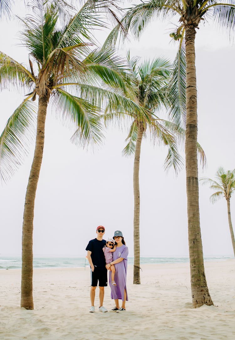 Loving Family In Sunglasses Among Palms On Sandy Beach