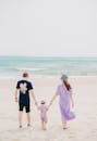 Father and mother holding hands with child on sunny beach
