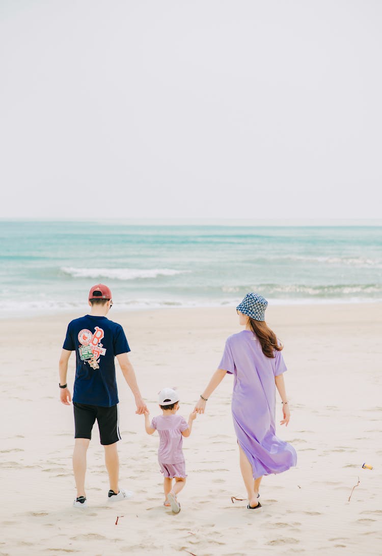 Father And Mother Holding Hands With Child On Sunny Beach