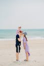 Wife kissing husband with child on shoulders on sandy beach