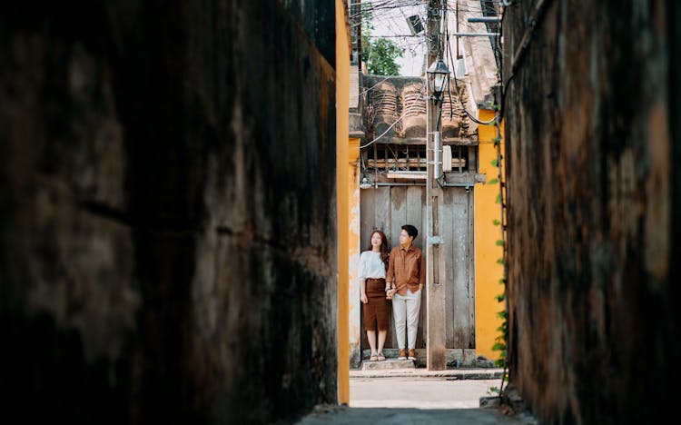 Stylish Ethnic Couple Holding Hands Near Old Small House