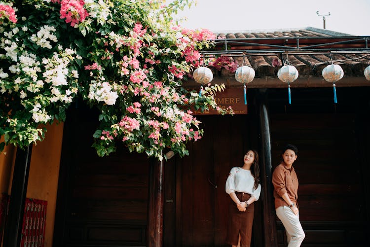 Romantic Young Ethnic Couple Standing Near House And Looking Away Dreamily