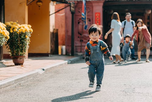 Free Happy ethnic toddler running away from parents during walk in park Stock Photo