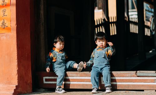 Free Cute twin children in denim outfits sitting outdoors on a sunny day. Stock Photo